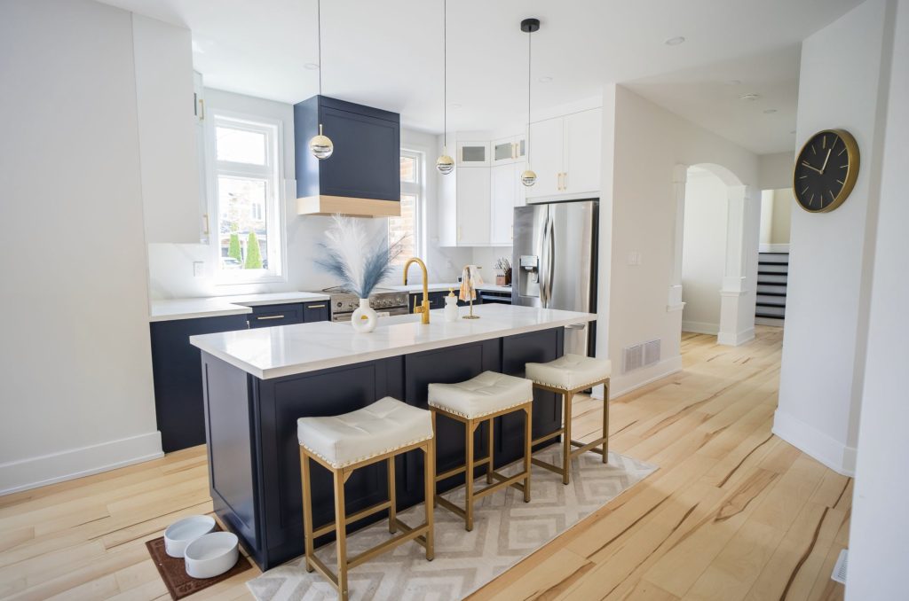 Navy island with three stools under brass pendants